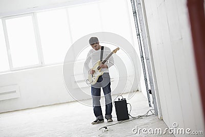 Man Playing Electric Guitar In Warehouse