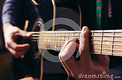 Man playing music at black wooden acoustic guitar