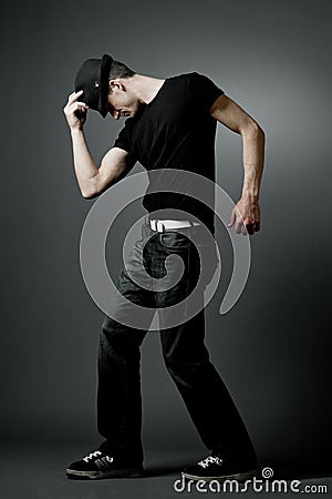 Man posing in black t-shirt and black hat.