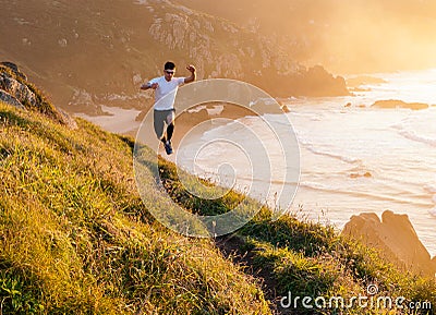 Man practicing trail running and leaping in a path in the coast