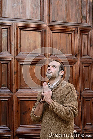Man praying in front of the church holding prayer beads