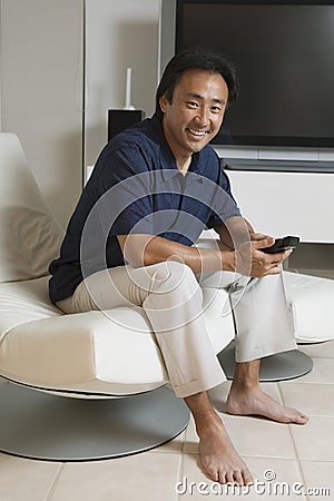 Man With Remote Control In Front Of Large TV Screen At Home