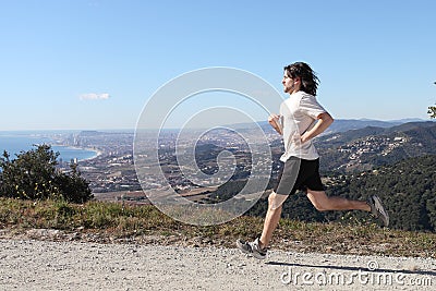 Man running in the mountain with a big city in the background