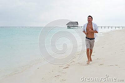 Man runs along the beach on the background of the sea