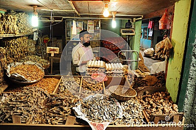 Man selling dry fish on market, India