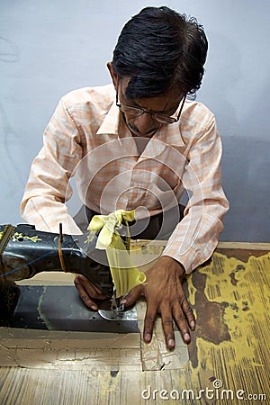 Man sewing several pieces of clothes in Agra for Pushpanjali