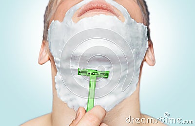 Man is shaving with green razor