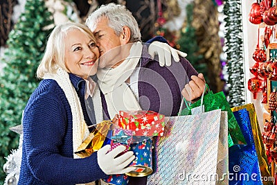 Man With Shopping Bags Kissing Woman At Store