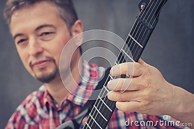 Man in short sleeve shirt playing electric guitar