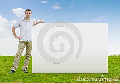 Man standing in a field with a blank sign