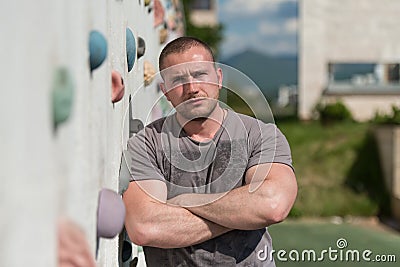 Man Stands In Front Of An Outdoors Climbing Wall