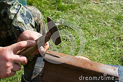 The man straightens rusty nails with a hammer