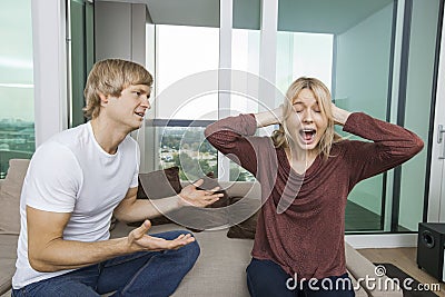 Man trying to talk as woman yells out aloud in living room at home