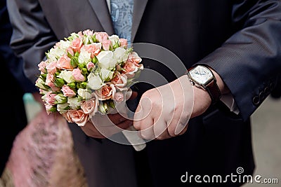 Man with watch hands a flower bouquet