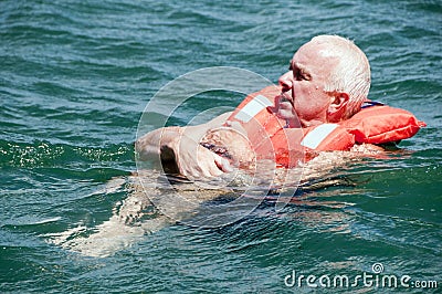 Man in water in life jacket in the huddle position