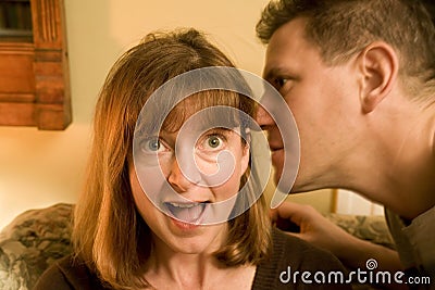 Man whispering in ear of woman