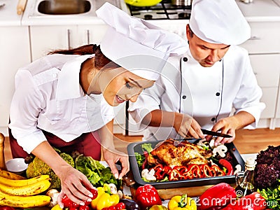 Man and woman in chef hat cooking chicken