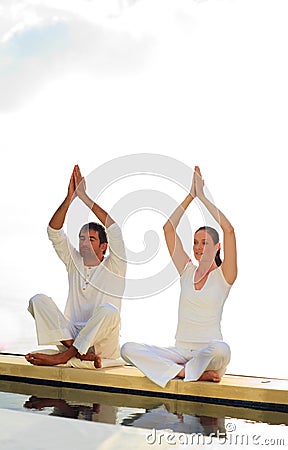 Man and woman doing yoga near the sea