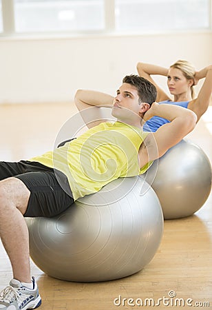 Man And Woman Exercising On Pilates At Health Club