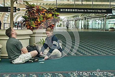 Man & Woman Pass Time with Card Games at Airport