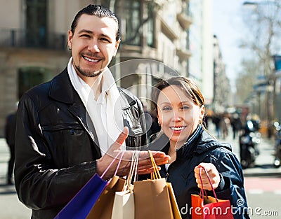 Man and woman with shopping bags at street