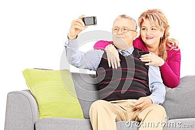 Man and woman on a sofa taking pictures of themselves with phone