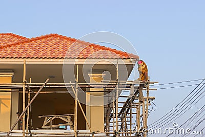 Man worker on scaffold painting roof