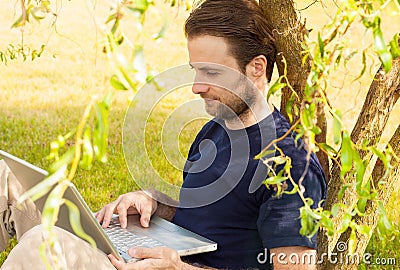 Man working on laptop computer outdoor in a park