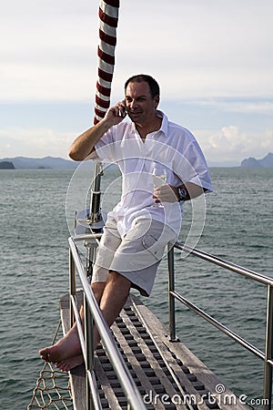 Man on yacht with mobile phone and wine