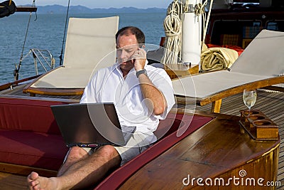 Man on yacht with phone and laptop