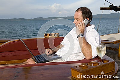 Man on yacht with phone and laptop