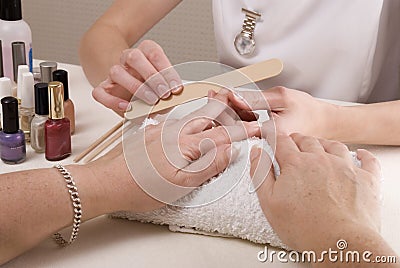 Manicurist filing womans nails