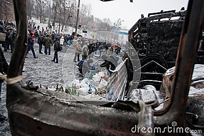 Many active people walk around the winter snowy street with burned cars and buses during anti-government protest Euromaidan