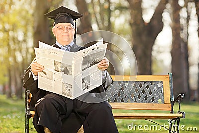 Mature college professor reading newspaper in park