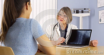 Mature doctor explaining neck x-ray to Mexican woman patient