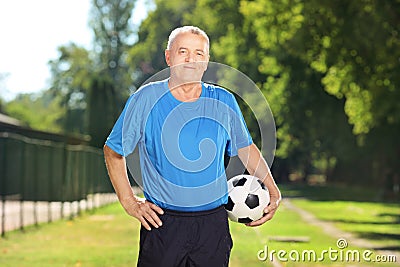 Mature man in sportswear holding a ball in a park