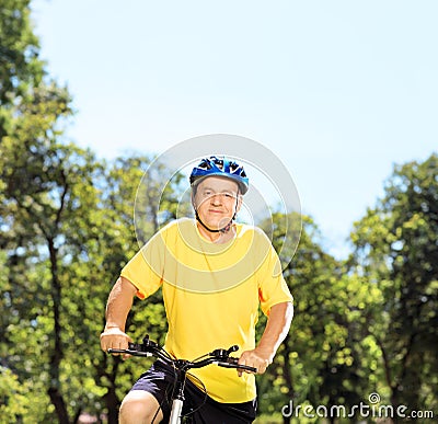 Mature man in sportswear posing on a mountain bike in a park