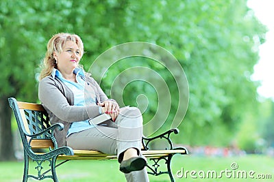 Mature pensive woman sitting alone in park