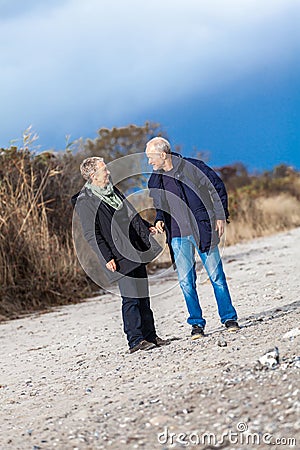 Mature senior couple walking on the beach autumn winter