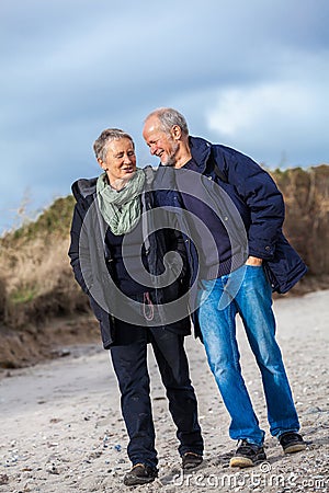 Mature senior couple walking on the beach autumn winter