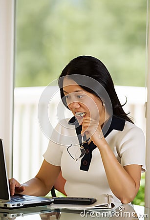 Mature woman biting her eye glasses in anger while working from