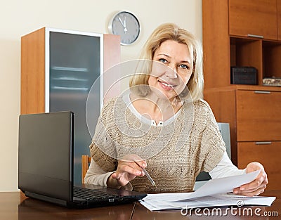 Mature woman with financial documents at table