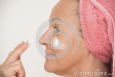 Mature woman putting cream on face