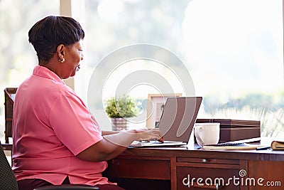 Mature Woman Using Laptop On Desk At Home