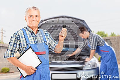  car key and another mechanic performing a car check in the background