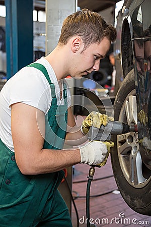 Mechanic replacing the tire or wheel on a car in garage or workshop