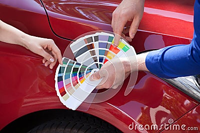 Mechanic showing color samples to customer against car