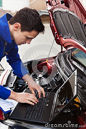 Mechanic using laptop while repairing car