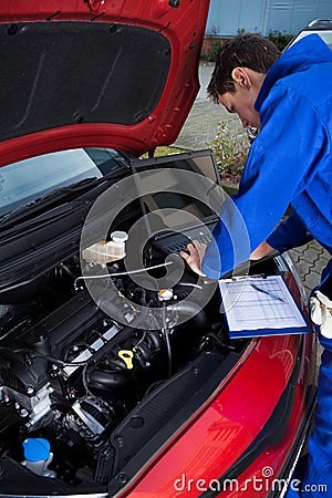 Mechanic using laptop while repairing car