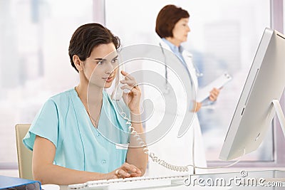 Medical assistant on phone, using computer